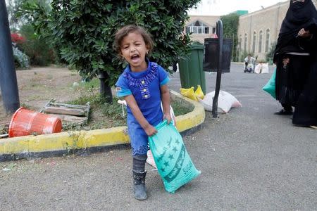 A girl screams for help to her mother while she carries food supplies she received from a local charity in Sanaa, Yemen, June 23, 2016. REUTERS/Mohamed al-Sayaghi/Files