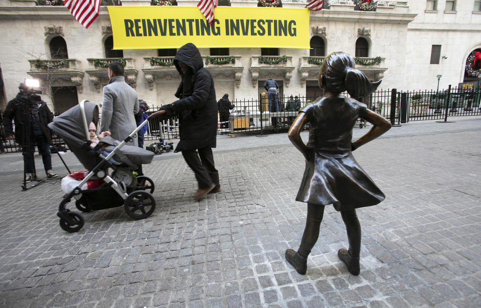 People pass the "Fearless Girl" statue after it was unveiled at its new location in front of the New York Stock Exchange, Monday, Dec. 10, 2018, in New York. The statue, considered by many to symbolize female empowerment, was previously located near the Charging Bull statue on lower Broadway. (AP Photo/Mark Lennihan)