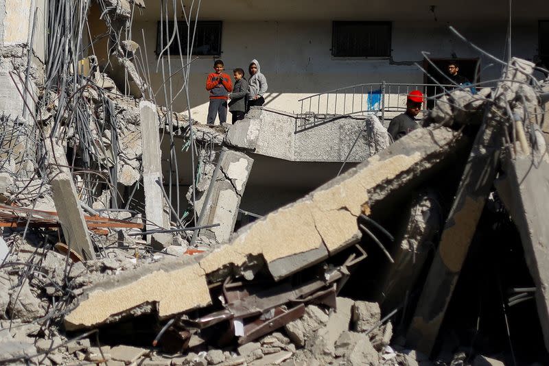 Niños palestinos miran mientras permanecen de pie en el lugar de un ataque aéreo israelí contra un edificio en Ráfah