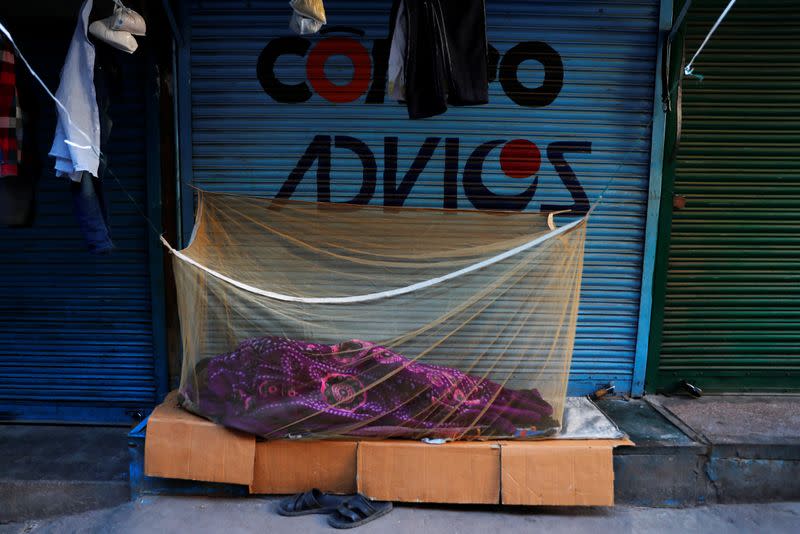 A migrant worker sleeps outside a closed shop at a wholesale market in the old quarters of New Delhi, during a 21-day nationwide lockdown to slow the spreading of the coronavirus disease (COVID-19)