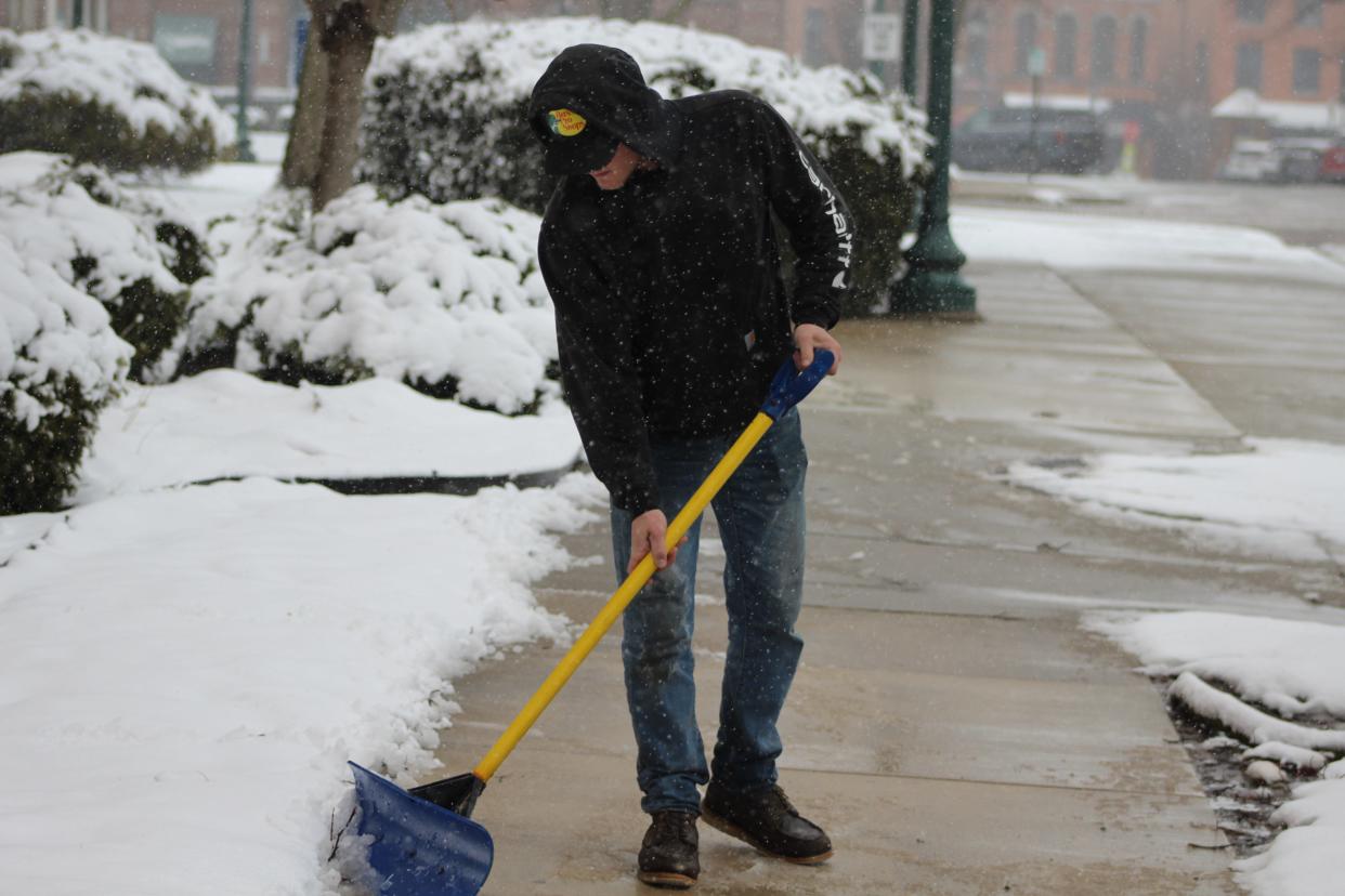 Josh McGee of Gagne's Lawn Service in Monroe clears slushy snow Friday from the sidewalk at First Presbyterian Church on Washington Street.