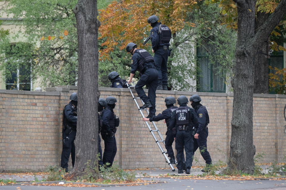 Police officers cross a wall at a crime scene in Halle, Germany, Wednesday, Oct. 9, 2019 after a shooting incident. A gunman fired several shots on Wednesday in the German city of Halle. Police say a person has been arrested after a shooting that left two people dead. (Sebastian Willnow/dpa via AP)