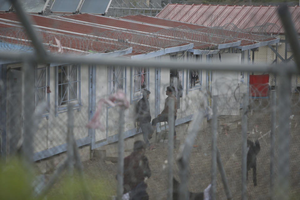 Migrants who were arrested after crossing illegally from Turkey to Greece stand behind a fence at a detention center near the village of Fylakio, at the Greek-Turkish border, Greece, Friday, May 21, 2021. An automated hi-tech surveillance network being built on the Greek-Turkish border aiming at detecting migrants early and deterring them from crossing, with river and land patrols using searchlights and long-range acoustic devices. (AP Photo/Giannis Papanikos)