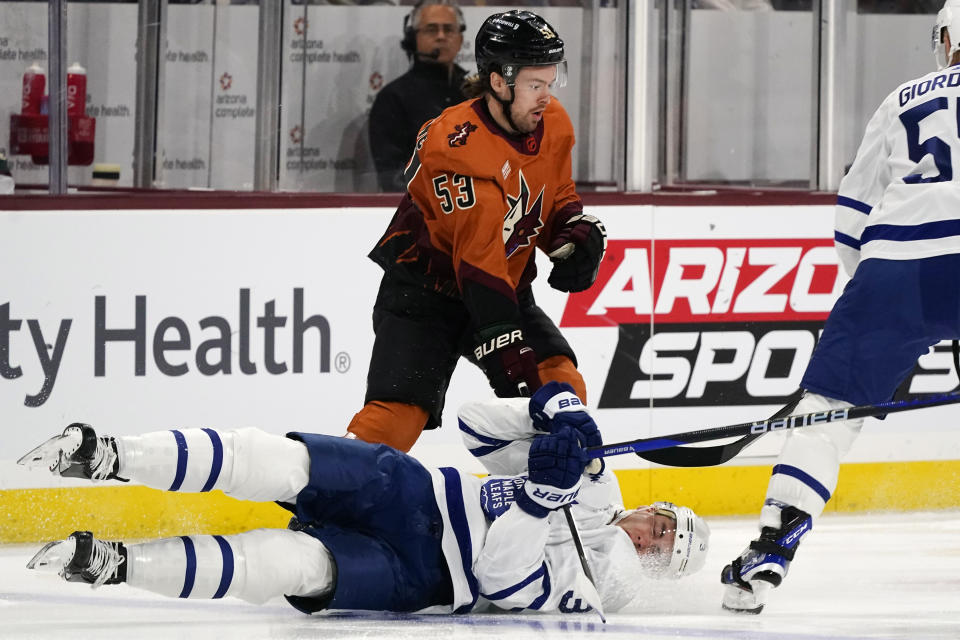 Arizona Coyotes left wing Michael Carcone (53) sends Toronto Maple Leafs defenseman Justin Holl (3) to the ice during the first period of an NHL hockey game in Tempe, Ariz., Thursday, Dec. 29, 2022. (AP Photo/Ross D. Franklin)