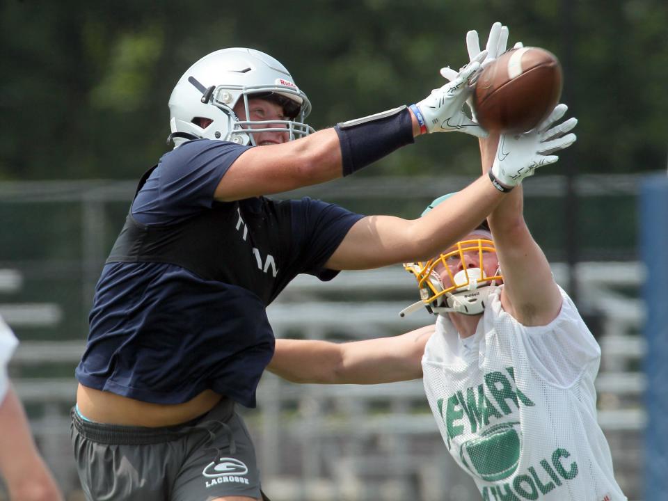 Granville's Kyle Kirby reaches for a pass under pressure from Newark Catholic's Owen Helms during a scrimmage on Tuesday.
