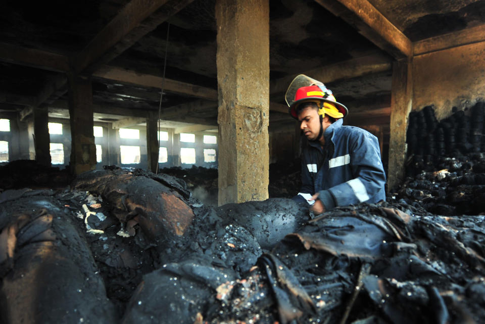 A Bangladeshi police official inspects the burnt garment factory in the Savar neighborhood outside Dhaka, Bangladesh, Sunday Nov. 25, 2012. At least 112 people were killed in a late Saturday night fire that raced through the multi-story garment factory just outside of Bangladesh's capital, an official said Sunday.(AP Photo/ khurshed Rinku)