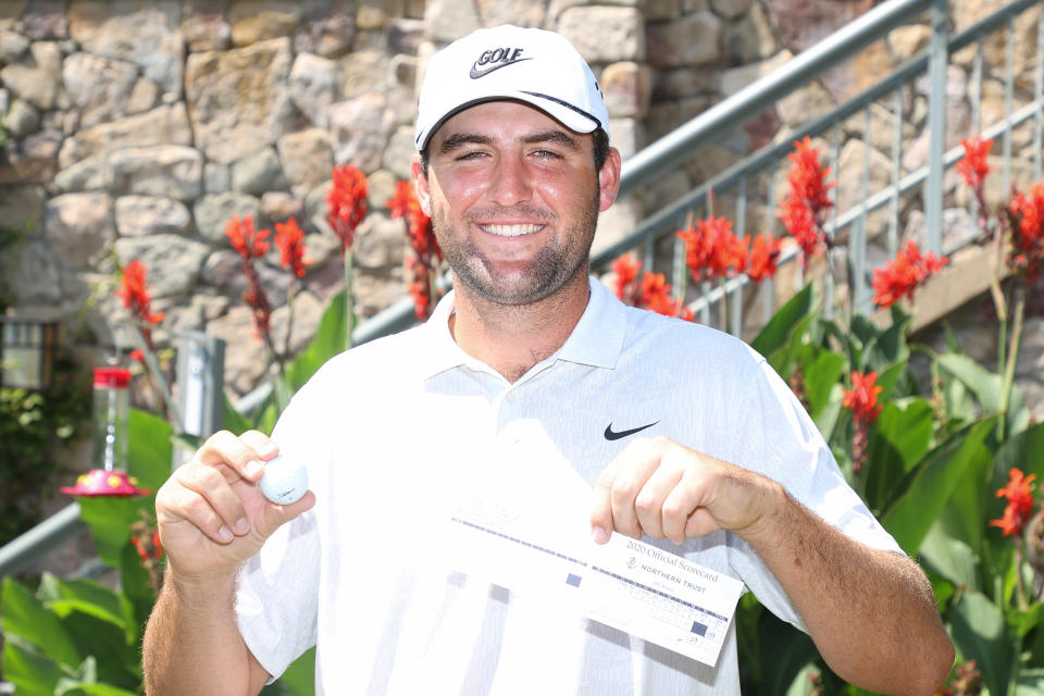 Scottie Scheffler holding up his ball and scorecard