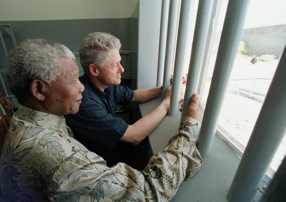FILE - Nelson Mandela, left, and former US president Bill Clinton look to the outside from Mandela's Robben Island prison cell in Cape Town, South Africa, March 27, 1998. The South African government announced Friday Jan. 19, 2024 that it plans to challenge an auction of artifacts which belonged to Mandela, set to take place in New York next month. (AP Photo/Scott Applewhite, Pool, File)