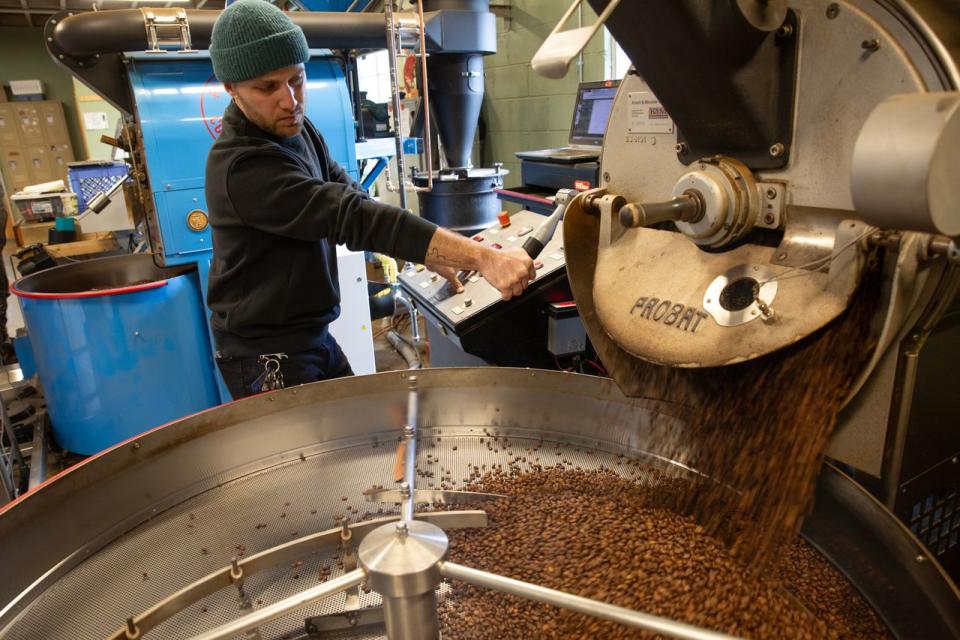 Zach Wiley operating a roasting machine at Red Rooster Coffee.