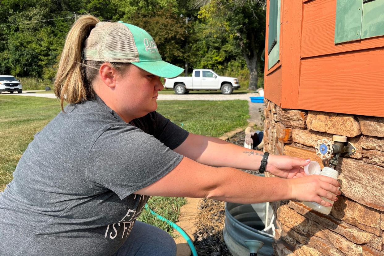 Allison Roderick, environmental health officer for Webster County, Iowa, draws a sample of well water from a home near Fort Dodge, Iowa. Roderick sends the samples to a lab to test for bacteria, nitrates, sulfates, arsenic, and manganese.