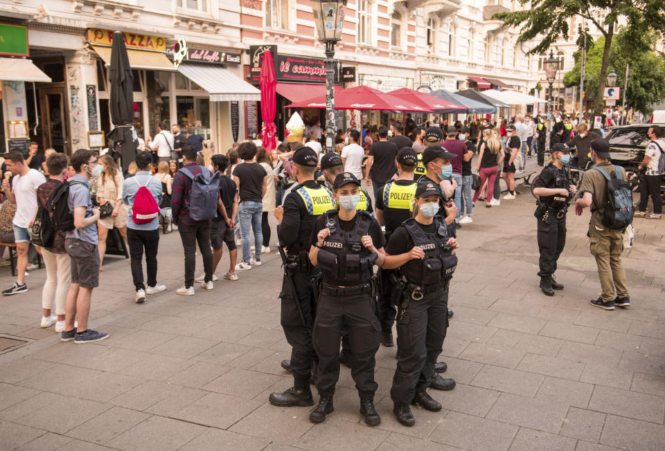 Police officers stand in the evening in the Schanzenviertel on the street "Schulterblatt" and control the coronavirus rules, in Hamburg, Germany, Friday, June 4, 2021. In the Schanzenviertel, alcohol may no longer be served outside on the weekend. (Daniel Bockwoldt/dpa via AP)