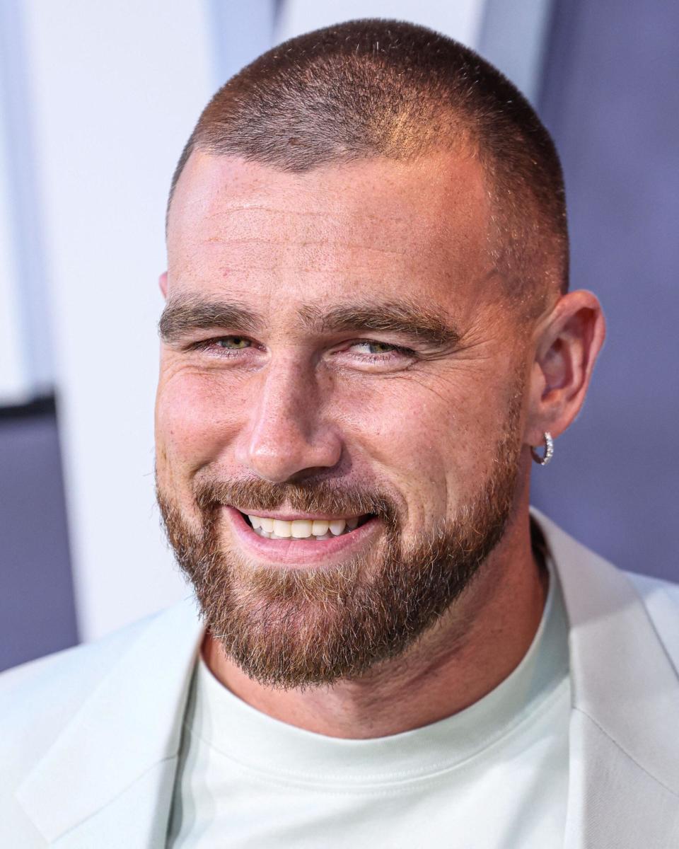 Travis Kelce smiles in a baby blue suit