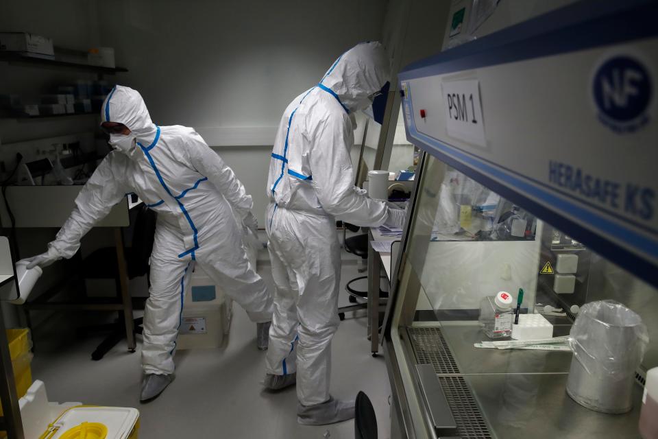 French lab scientists in hazmat gear inserting liquid in test tube manipulate potentially infected patient samples at Pasteur Institute in Paris, Thursday, Feb. 6, 2020. Scientists at the Pasteur Institute developed and shared a quick test for the new virus that is spreading worldwide, and are using genetic information about the coronavirus to develop a potential vaccine and treatments. (AP Photo/Francois Mori)