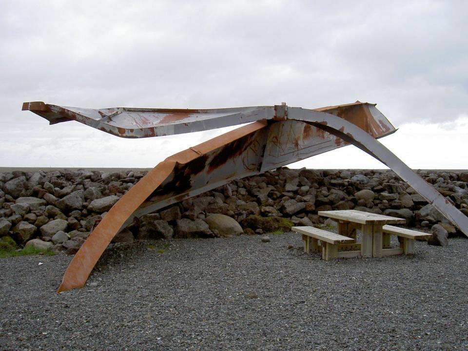 Twisted steel beams near a picnic table.