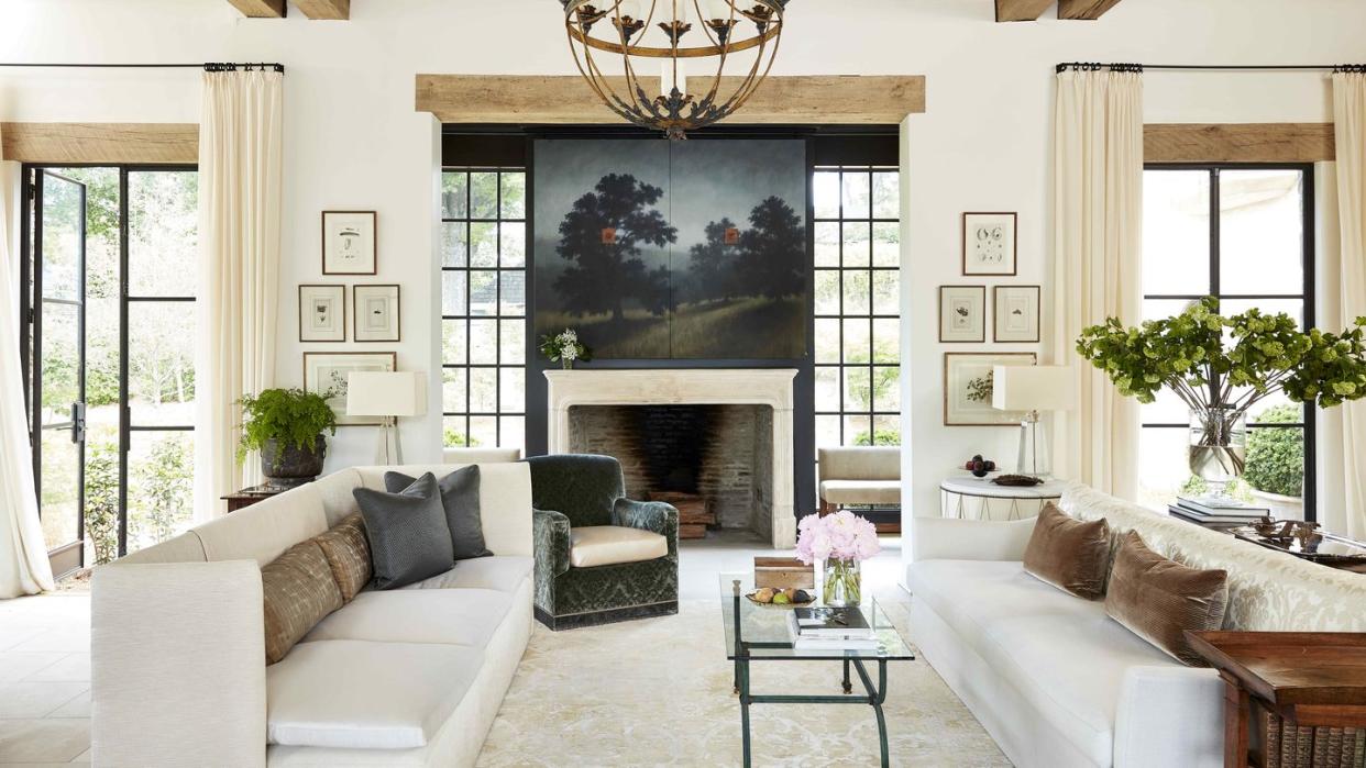 two sofas face each other in a large living space with a landscape painting hanging above the fireplace