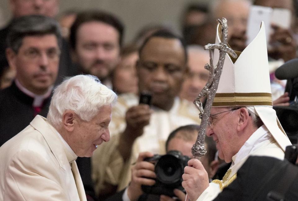 FILE -- In this file photo taken in the St. Peter's Basilica at the Vatican, on Feb. 22, 2014, Pope Francis salutes Pope Emeritus Benedict XVI, left, at the end of a consistory. When Pope Benedict XVI abdicated, he insisted he would remain "hidden from the world" in prayer. But Francis has slowly coaxed him out of retirement and giving him an increasily public role in the church, believing that he like all elderly have something to offer and shouldn't be holed up in a museum like a "statue." (AP Photo/Alessandra Tarantino)