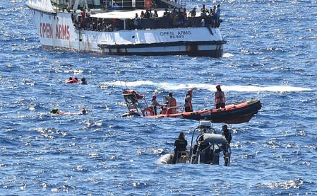 Migrants jump off the Spanish rescue ship Open Arms, close to the Italian shore in Lampedusa