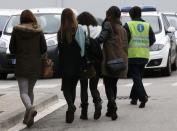 An assistant (R) escorts people believed to be family members of those killed in Germanwings plane crash as they arrive at Barcelona's El Prat airport March 24, 2015. REUTERS/Gustau Nacarino