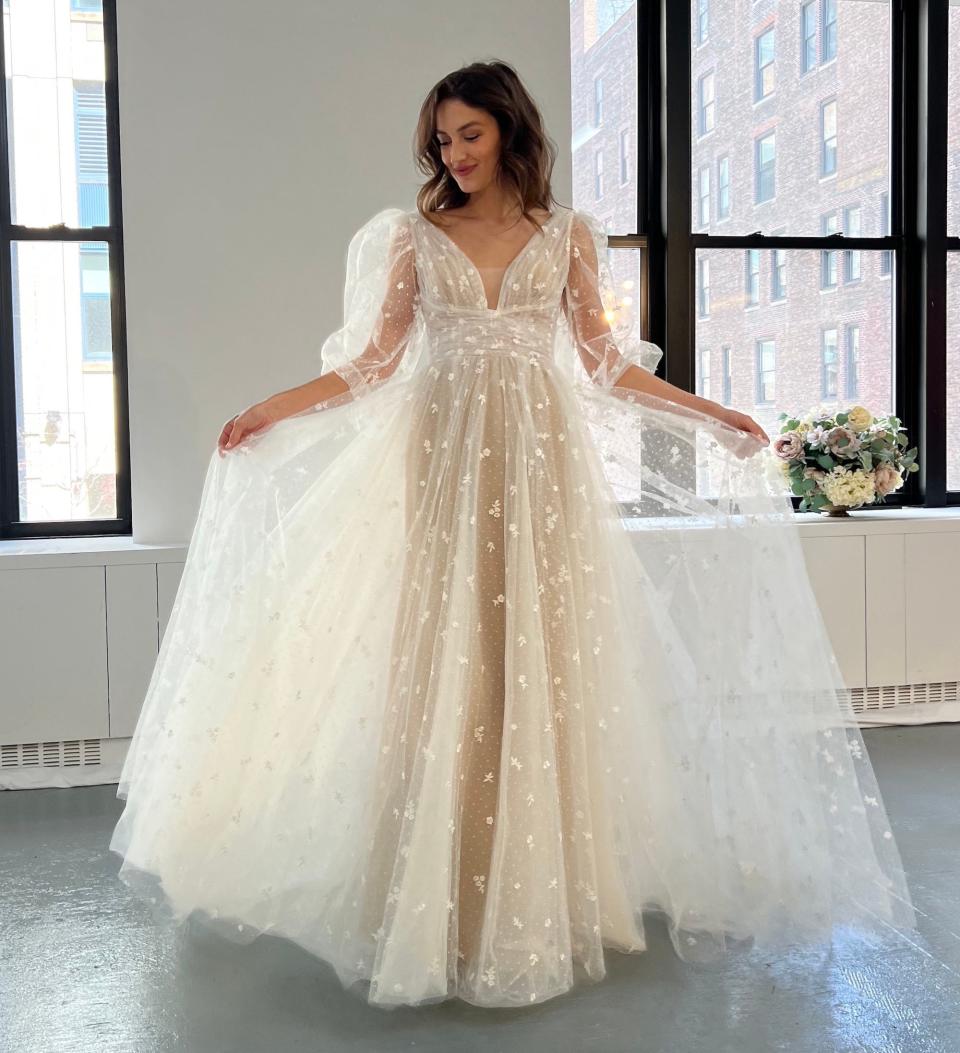 A woman in a wedding dress raises her gown's fulls skirt.