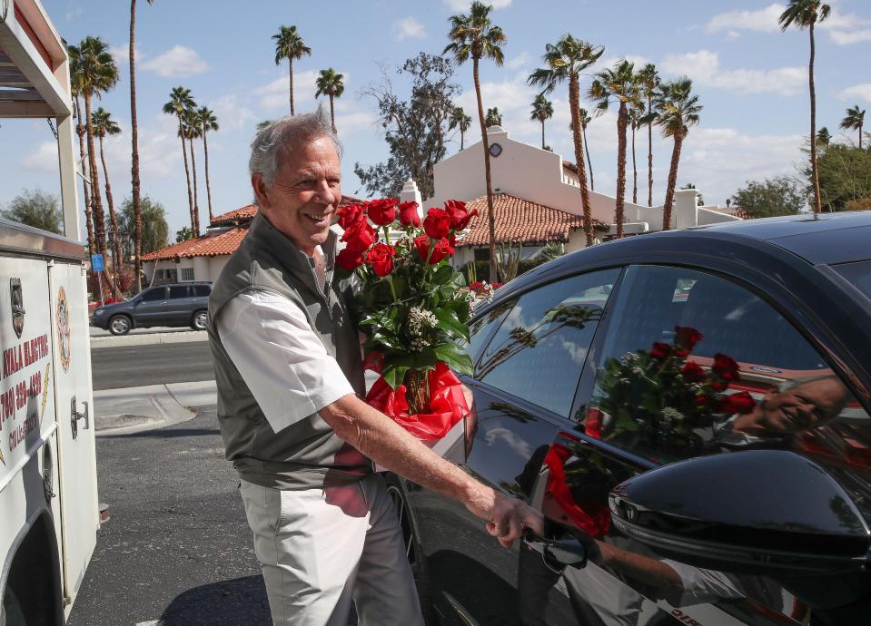 Larry Feiner loads a Valentine's Day bouquet into his car in 2023 for his wife Karen purchased from a florist in Rancho Mirage, Calif.