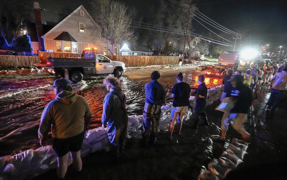 People work to protect homes into the night along 1700 South in Salt Lake City from the rising flow of Emigration Creek through Wasatch Hollow Park on Wednesday, April 12, 2023. As rapid snowmelt and possible April showers stoke fears of heavy flooding in the Northern Plains, state officials are announcing flood response plans, and residents are assembling thousands — if not hundreds of thousands — of sandbags to combat floods themselves. (Francisco Kjolseth/The Salt Lake Tribune via AP)