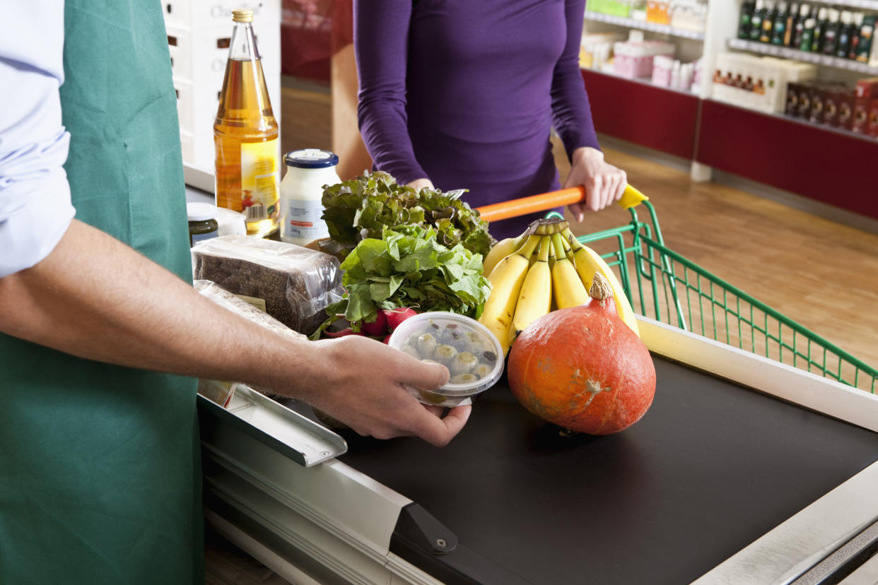 A cashier at a grocery store rings in items at a till. (Getty)