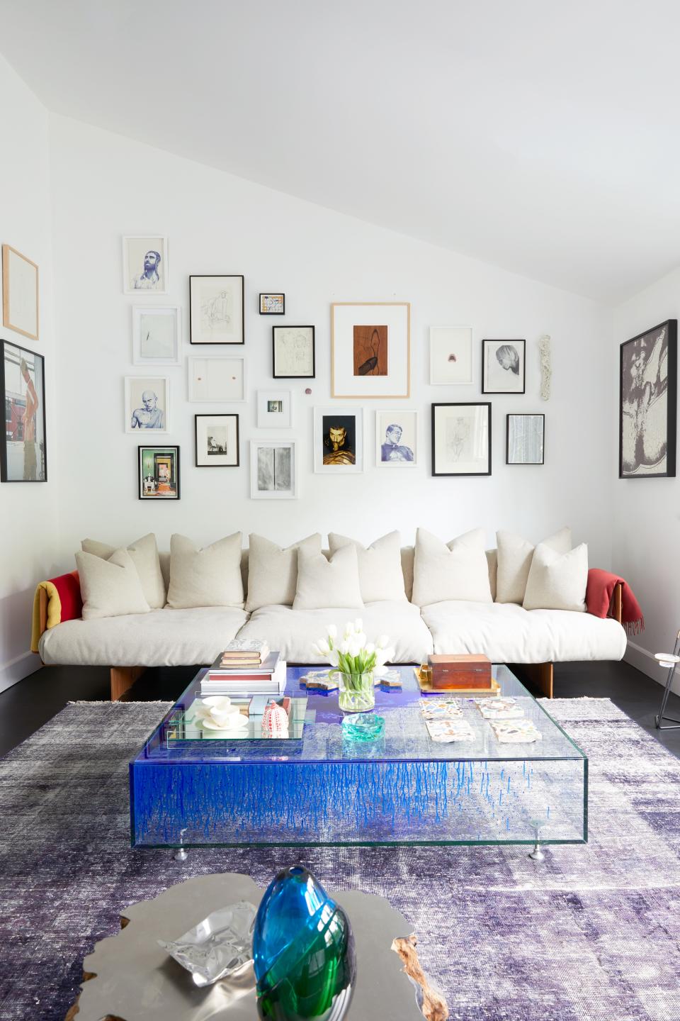 In the media room, the two men display what they call their “homoerotic collection.” Aside from nudes and depictions of sex acts, the wall shows an image of influential American artist Cindy Sherman in male drag. “All of these works have to do with different concepts of masculinity through an erotic lens,” explains Steele. The pillowed sofa is by contemporary Brazilian designer Jader Almeida, and the custom glass coffee table is by Fredrikson Stallard.