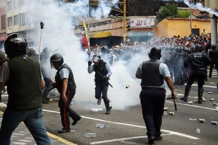 Police runs amidst tear gas as they clash with opposition students during a march against President Nicolas Maduro's government in San Cristobal February 12, 2015. REUTERS/Carlos Eduardo Ramirez