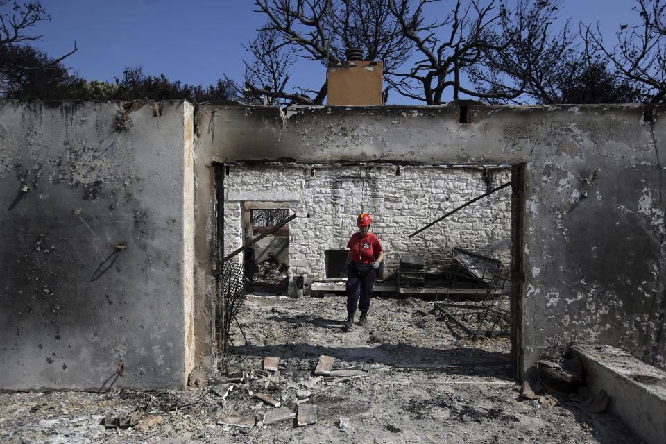 A member of a rescue team searches a burned house in Mati, east of Athens, Wednesday, July 25, 2018. Rescue crews were searching Wednesday through charred homes and cars for those still missing after the deadliest wildfires to hit Greece in decades decimated seaside areas near Athens, killing at least 79 people and sending thousands fleeing. (AP Photo/Thanassis Stavrakis)