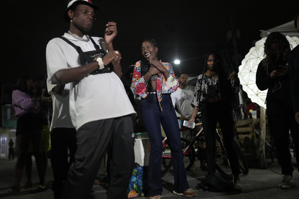 People attend the Gas Battle rapping competition outside a bar in the City of God favela of Rio de Janeiro, Brazil, late Wednesday, Nov. 10, 2021. Rap artists in the favela are starting to compete again since the COVID-19 pandemic curtailed public gatherings, presenting local residents with a show in a sign of a return to normalcy for music lovers. (AP Photo/Silvia Izquierdo)