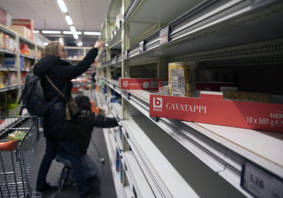 Two women look for pasta on nearly empty shelves of a supermarket in Antwerp, Belgium, Friday, March 13, 2020. Belgium announced sweeping measures on Thursday, including the closure of all schools, restaurants and bars as well as cancelling sporting and cultural events, in an effort to curb the spread of the virus. For most people, the new coronavirus causes only mild or moderate symptoms, such as fever and cough. For some, especially older adults and people with existing health problems, it can cause more severe illness, including pneumonia. (AP Photo/Virginia Mayo)