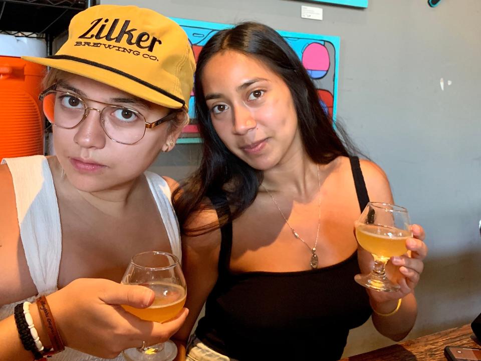 The author with a friend in a bar holding glasses of beer with artwork on a gray wall behind them