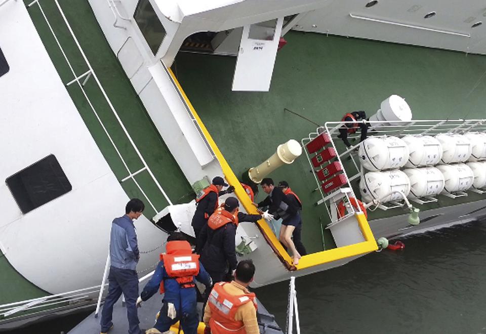 FILE - In this April 16, 2014 file photo released by South Korea Coast Guard via Yonhap News Agency, South Korean coast guard officers rescue ferry Sewol captain Lee Joon-seok, wearing a sweater and underwear, from the ferry in the water off the Jindo, South Korea. Salvage workers are slowly pulling up the huge, corroded South Korean ferry above the sea surface Thursday, March 23, 2017, about three years after it sank on its routine voyage to a resort island, killing more than 300 people, mostly high school students. (South Korea Coast Guard/Yonhap via AP, File)