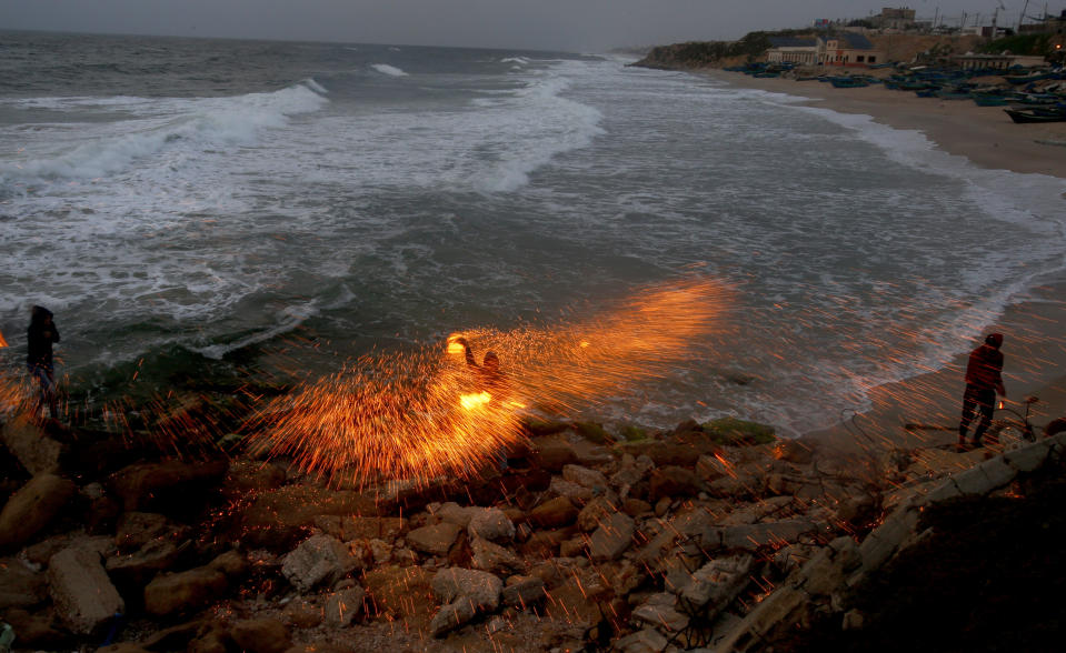 A man swings fireworks during the Muslim holy fasting month of Ramadan, on the beach of Gaza City, Monday, April 26, 2021. (AP Photo/Hatem Moussa)