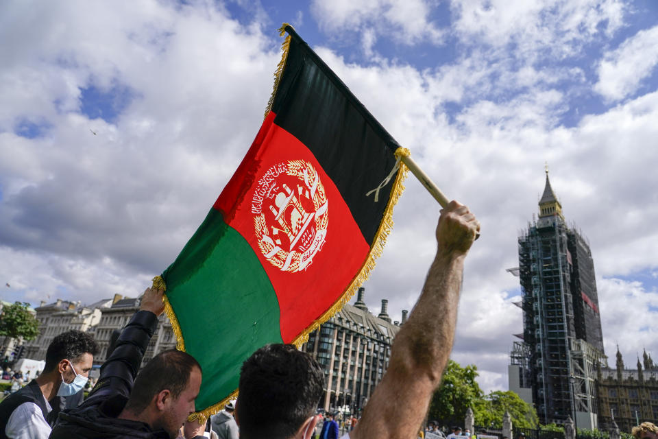 A demonstrator walks holding an Afghanistan flag, during a protest at Parliament Square in London, Wednesday, Aug. 18, 2021. British Prime Minister Boris Johnson is set to update lawmakers Wednesday about the evacuation of British nationals and local allies from Afghanistan. Big Ben's clock tower shrouded in scaffolding, right. (AP Photo/ Alberto Pezzali)