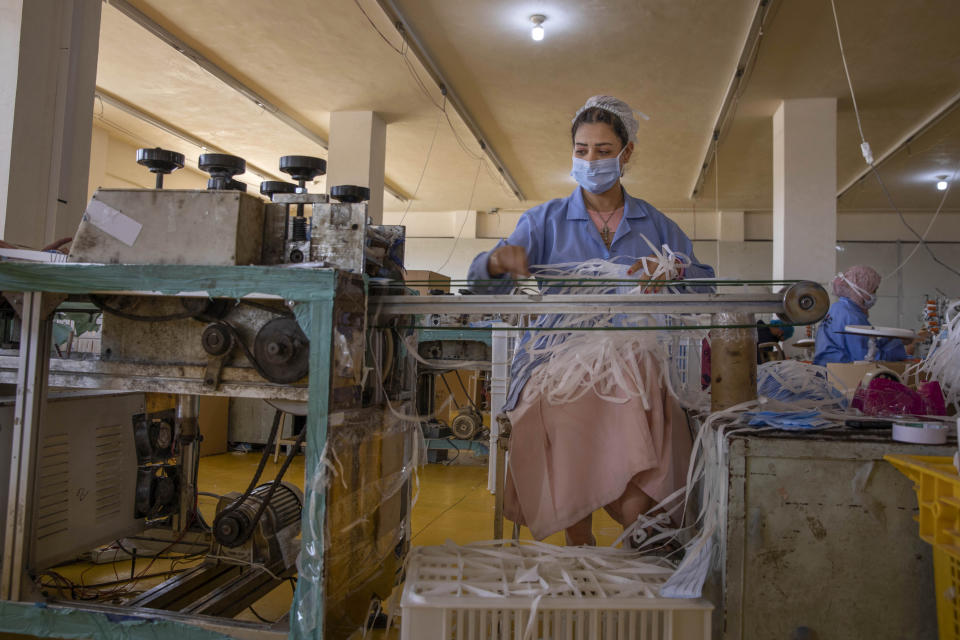 A woman working at Medic Egypt for Medical Clothes company makes protective face masks to be used to help curb the spread of the coronavirus at a factory in Menoufiya, Egypt, Saturday, June 6, 2020. Egypt has officially ordered its people to wear face masks in public and private transportation, inside government business and offices as it is easing the partial lockdown imposed. Prime Minister Mustafa Madbouly has said violators would be fined as the country has seen a jump of daily reported infections in the past week. (AP Photo/Nariman El-Mofty)