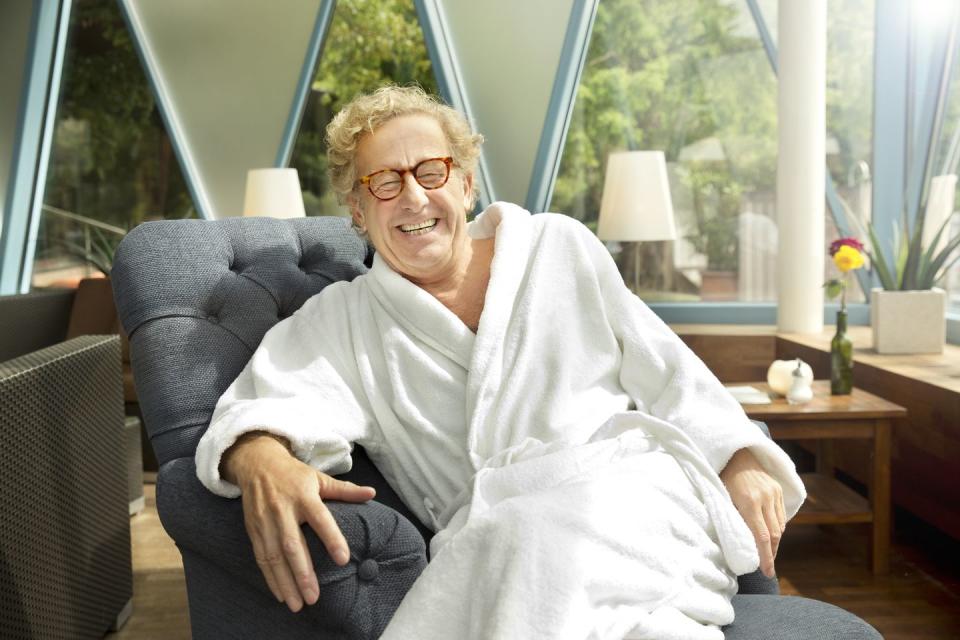 laughing senior man in bathrobe sitting in armchair