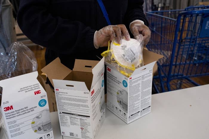 An employee unboxes N95 masks as people come to retrieve them as part of a government strategy to reduce the spread of COVID-19 at Meijer in Southfield, Michigan, Jan. 25, 2022.