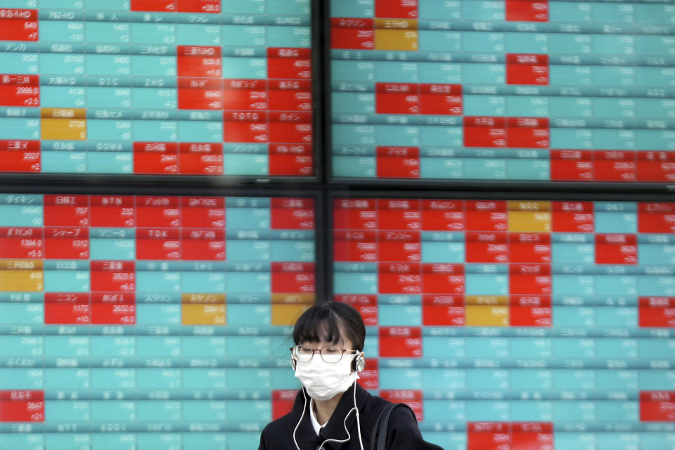 A woman wearing a protective mask stands in front of an electronic stock board showing Japan's Nikkei 225 index at a securities firm Thursday, Nov. 18, 2021, in Tokyo. Asian shares mostly declined Thursday after stock indexes shuffled lower on Wall Street. (AP Photo/Eugene Hoshiko)