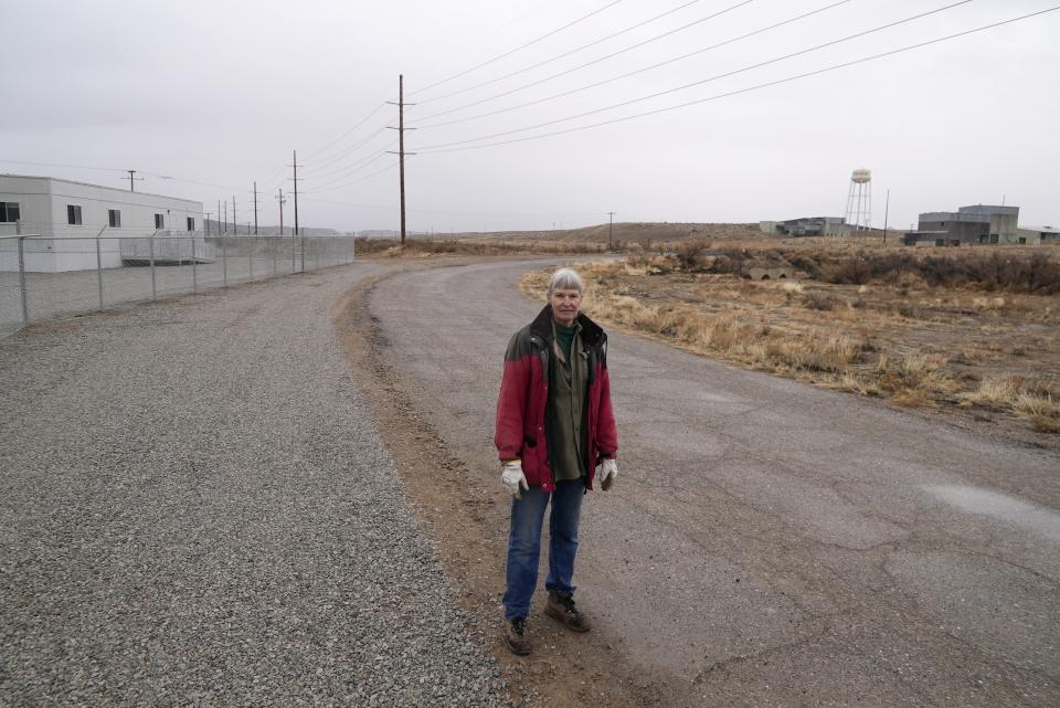 Gayna Salinas stands near a trailer, left, on land owned by Anson Resources, and a defunct uranium mine, right, Thursday, Jan. 25, 2024, in Green River, Utah. The Australian company with its U.S. subsidiaries is eyeing a nearby area to extract lithium. Salinas, whose family farms in the rural community, said she was skeptical about the project's benefits. (AP Photo/Brittany Peterson)