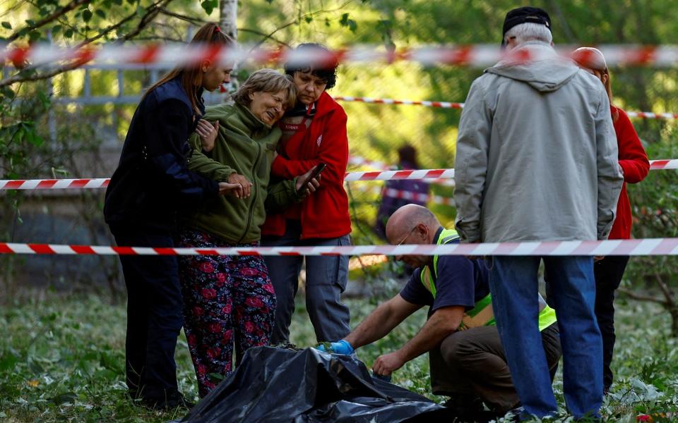 A woman reacts as she looks at the body of her granddaughter, who was killed during a Russian missile strike - VALENTYN OGIRENKO/REUTERS