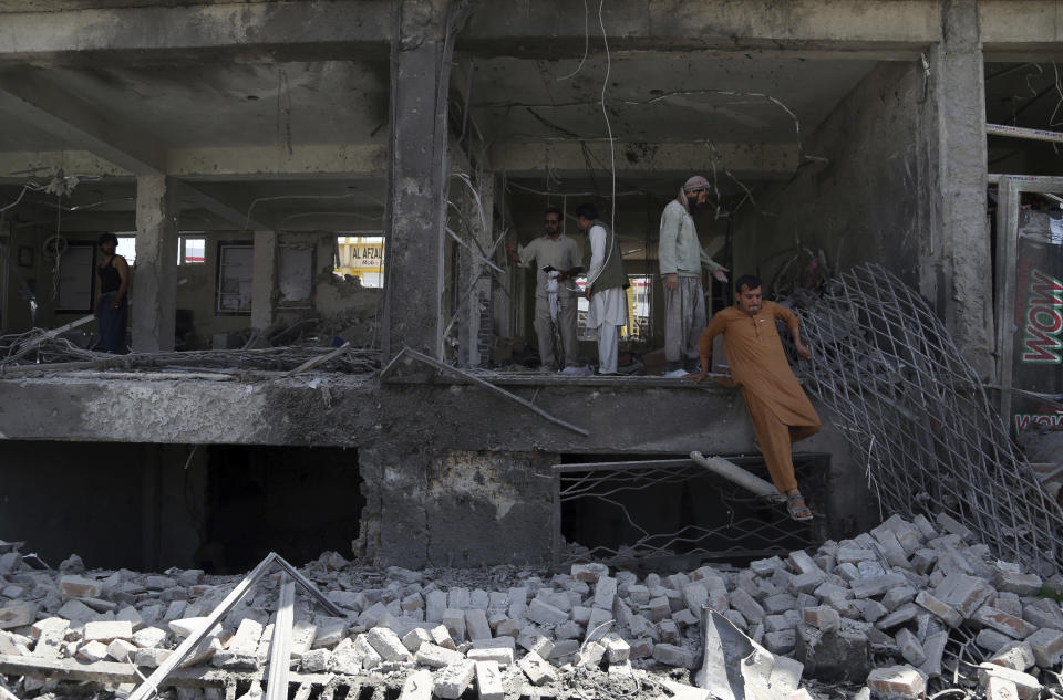 Afghan men searches for the remains of their belongings at their shops following a suicide attack in Kabul, Afghanistan, Thursday, July 25, 2019. Three bombings struck the Afghan capital on Thursday, killing at least eight people, including five women and one child, officials said Thursday. (AP Photo/Rahmat Gul)