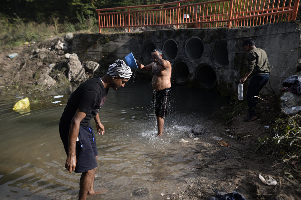 Migrants who are sleeping in a makeshift camp in a forest outside Velika Kladusa, Bosnia, clean themselves up in a nearby stream Friday, Sept. 25, 2020. Remote woods, abandoned run-down buildings and roadsides on the fringes of northwestern Bosnian towns are steadily filling with makeshift camps where migrants from the Middle East, Asia and North Africa are bracing for more misery as autumn's chill and rains set it. (AP Photo/Kemal Softic)