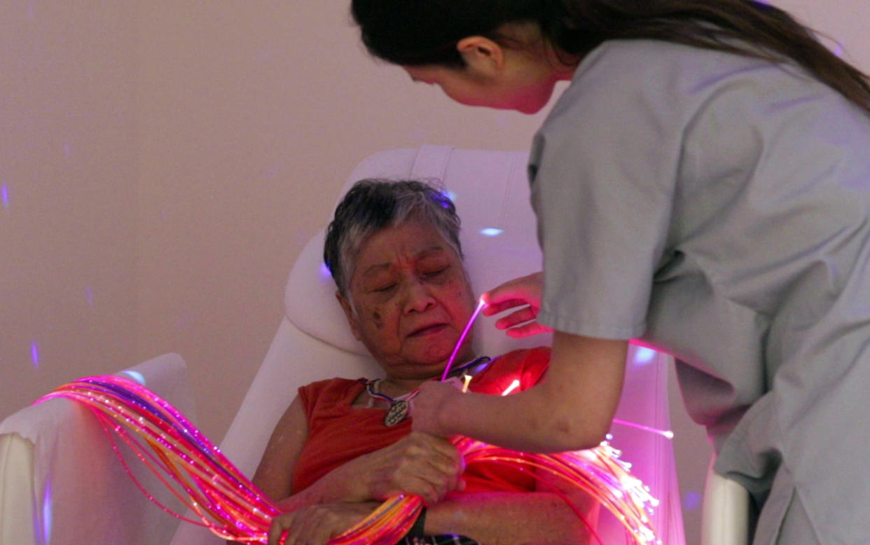 Guided by her therapist, Orange Valley Balestier Care Centre dementia resident Chua Mui Noi, 69, identifies the colours on fibre optic strands in a multi-sensory room. (PHOTO: Yahoo News Singapore)