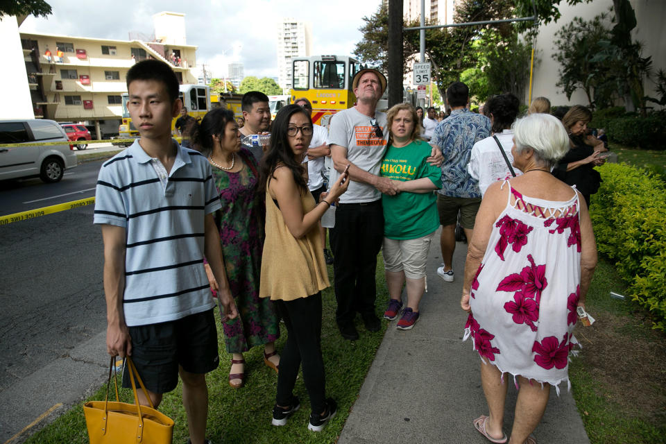 <p>Onlookers stand on a sidewalk as a fire burns at the Marco Polo apartment complex, Friday, July 14, 2017, in Honolulu, Hawaii. (Photo: Marco Garcia/AP) </p>