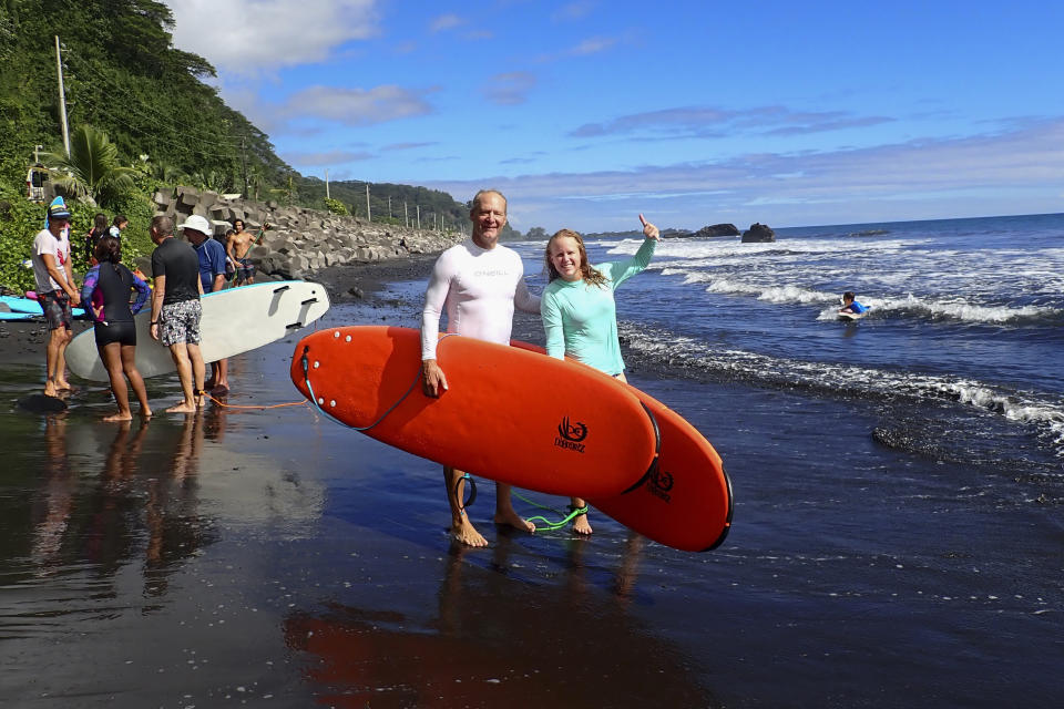 Kristen Pankratz, right, and her father David pose ahead of a surf in Tahiti on May 19, 2020. Since she was 4 years old, Kristen Pankratz has shared in dad's dream to sail around the world. Pankratz gave up her advertising job in Dallas and set sail with her parents in January. But now, along with hundreds of other sailors, the family finds themselves stranded in paradise.They made it as far as Tahiti in remote French Polynesia, one of the last places to offer refuge as borders slammed shut. (Kristen Pankaratz via AP)