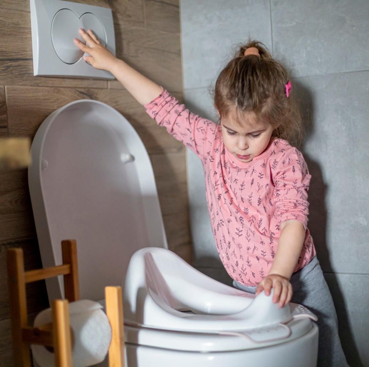 Little girl uses toilet with adapter