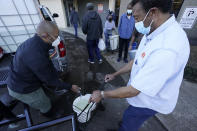 FILE - In this Feb. 22, 2021, file photo, City of Jackson councilman and State Rep. De'Keither Stamps, left, pours potable water into a resident's empty jugs and containers in Jackson, Miss. The snow and ice that crippled some states across the South has melted. But it has exposed the fragility of aging waterworks that experts have been warning about for years. Cities across Texas, Tennessee, Louisiana and Mississippi are still grappling with outages that crippled health care facilities and forced families to wait in line for potable water. (AP Photo/Rogelio V. Solis)