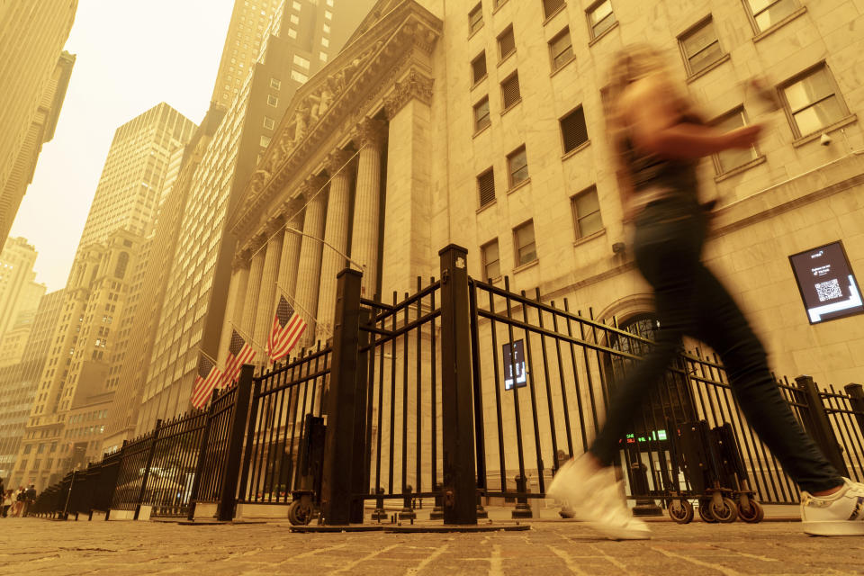 A pedestrian walks past the smoke and haze shrouded New York Stock Exchange building in New York City Wednesday, June 7, 2023. (AP Photo/J. David Ake)