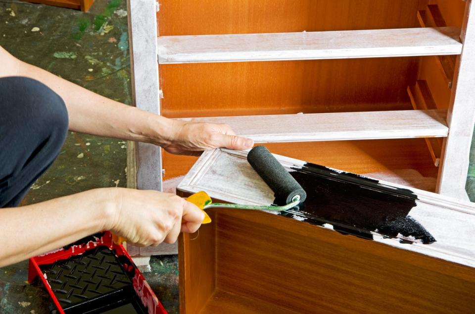 Person painting one drawer black of a dresser that is covered with primer